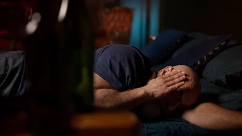 Middle-aged man wakes up in bed with headache after drinking liquor, hangover Stock Footage 342520882