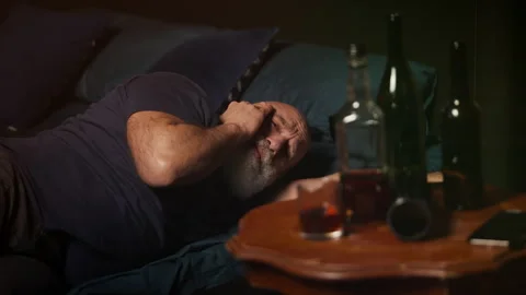 Middle-aged man wakes with hangover, struggling with alcohol addiction Stock Footage 346714368