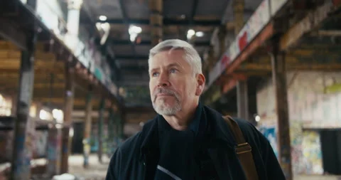 Middle aged man walking and looking around an abandoned factory. Stock Footage 300800433