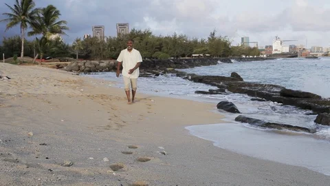 Middle-aged man walking barefoot on a beach. 스톡 동영상 88371796