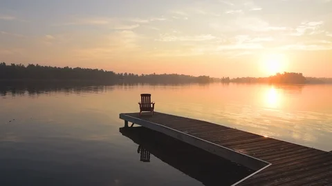 Middle aged man walking out onto dock at sunrise with coffee cup. Stock Footage 94263309