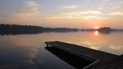 Middle aged man walking out onto dock at sunrise with camera. Stock Footage 95021593