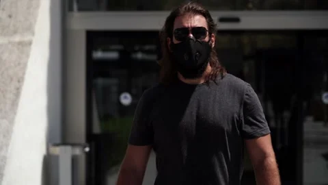 Middle aged man walking through the outdoors of the airport while wearing a m 스톡 동영상 136393548