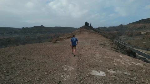 A middle-aged man walks towards a rock formation known as El Camello Stock Footage 228229857
