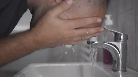 Middle aged man washing face with water in bathroom sink morning routine Stock Footage 342240547