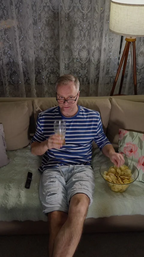 Middle-aged man watching TV with beer at night Stock Footage 302826882