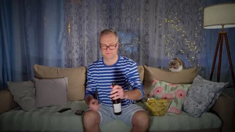 Middle-aged man watching TV with beer at night Stock Footage 302829761