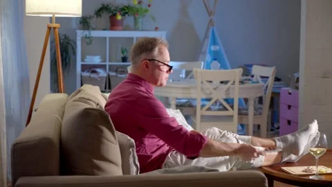 Middle-aged man watching TV with glass of wine at night Stock Footage 302843638