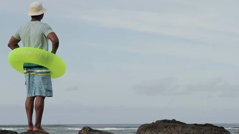 Middle-aged man wearing an inner tube by the sea. Stock-Footage 88370864