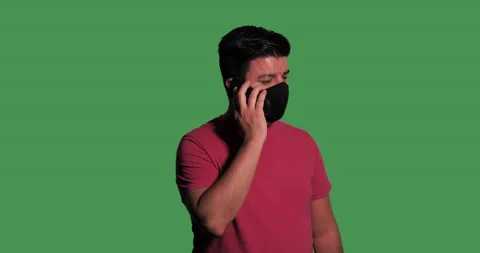 Middle-aged man wears mask and answers phone call in front of green screen. Stock Footage 139102907