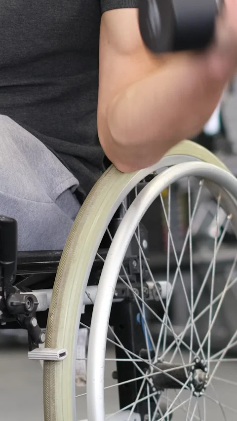 A middle-aged man in a wheelchair is working out in the gym. Vertical video Video stock 248424517