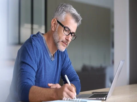 Middle-aged man working from home-office on laptop Stock Footage 81761433