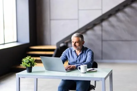 Middle-aged man working from home office on laptop 库存照片