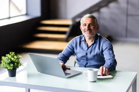 Middle-aged man working from home office on laptop 库存照片