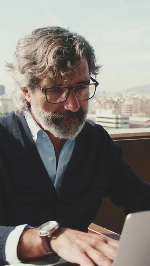 Middle-aged man working on laptop while sitting on balcony Stock Footage 229508187