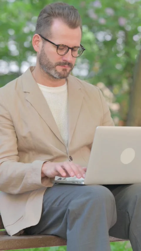 Middle Aged Man Working on Laptop while Sitting Outdoor on Bench, Vertical Video Stock-Footage 319012885