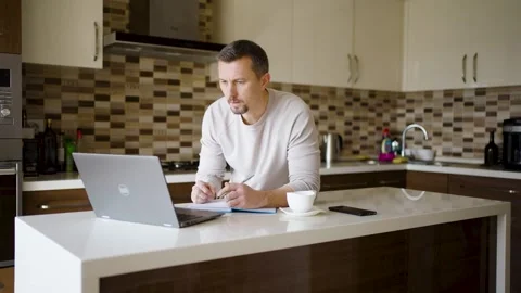 Middle-Aged Man Working on Laptop in Modern Kitchen. A man at kitchen using.. 스톡 동영상 331971331