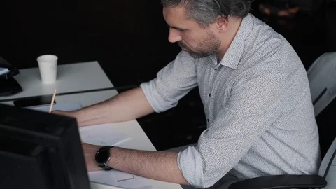 Middle-aged man works with documents and drawings while sitting at a table in Stock Footage 107768394