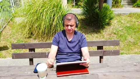 Middle-aged man works remotely in garden, in nature. Stock Footage 130874891