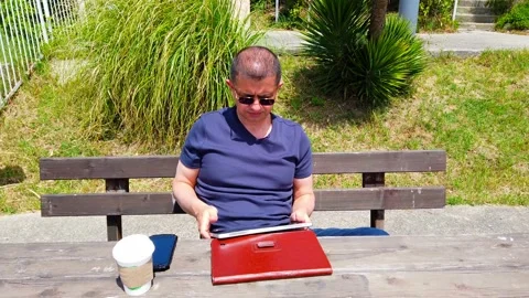 Middle-aged man works remotely in garden, in nature. Stock Footage 130874898
