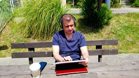 Middle-aged man works remotely in garden, in nature. Vídeos de archivo 130874907