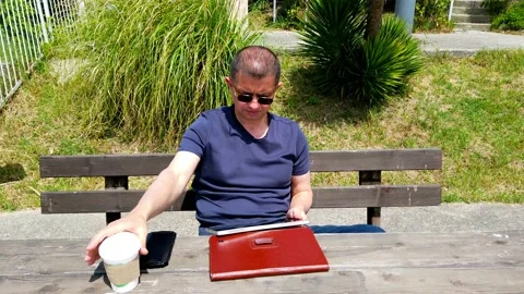 Middle-aged man works remotely in garden, in nature. Stock Footage 130874909