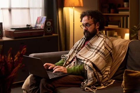 Middle Aged Man Wrapped in Blanket Working on Laptop at Home Stock Photos