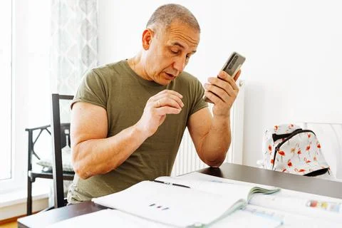 Middle-aged man writes notes in notebook Stock Photos