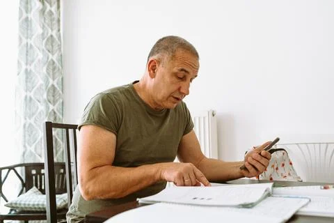 Middle-aged man writes notes in notebook Stock Photos