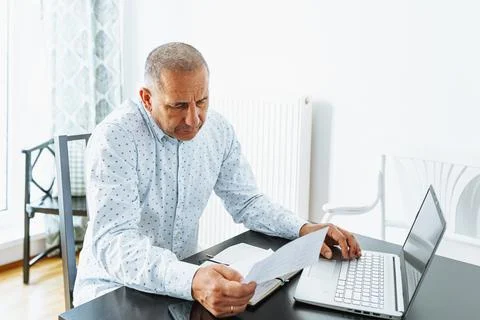 Middle-aged man writes notes in notebook Stock Photos
