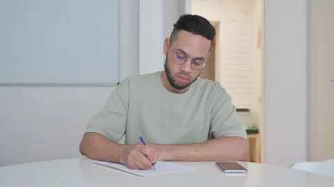 Middle Aged Man Writing while Sitting at Office Stockbeeldmateriaal 307916225
