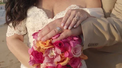 Middle aged married couple rest hands on flower bouquet on the beach. Stock Footage 135237264