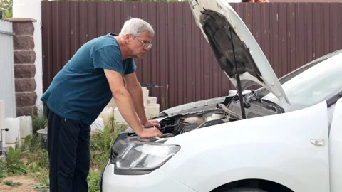 A middle-aged mechanic examines a malfunction in a car. Fixing the car yourself. Stock Footage 237692470