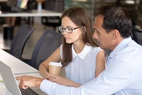 Middle aged mentor helping intern with computer work Stock Photos