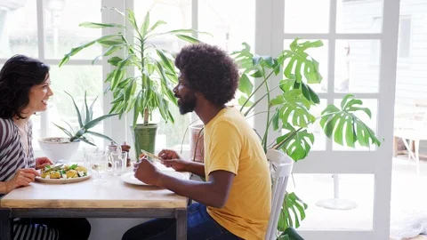 Middle aged mixed race couple eating lunch together at a table in a restaurant, 스톡 동영상 99753652