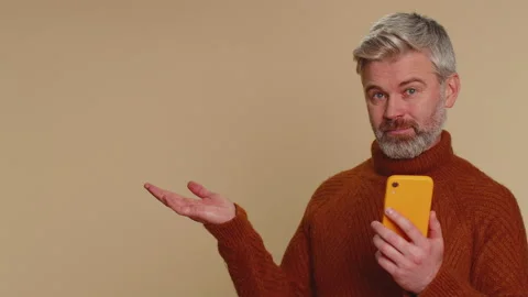 Middle-aged old man using smartphone pointing empty place, advertising area for Stock Footage 232444963