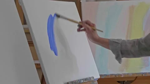 Middle aged painter makes the first blue brushstroke on a blank canvas Vídeos de archivo 147200942