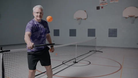 Middle aged pickleball player bouncing ball in front of the court Stock Footage 299432508