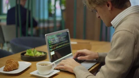 Middle aged programmer coding over breakfast in cafe Stock Footage 142381747