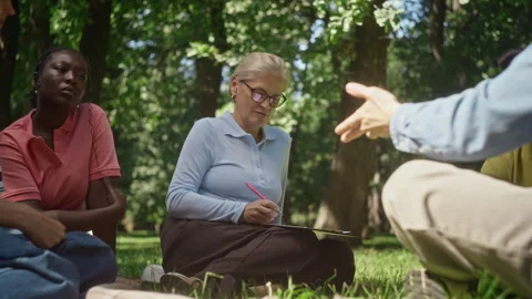 Middle Aged Psychologist Taking Notes in Outdoor Group Therapy 動画素材 344944457