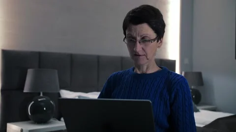 Middle aged senior woman using laptop at home.Adult lady try to figure out how Stock Footage 253240917