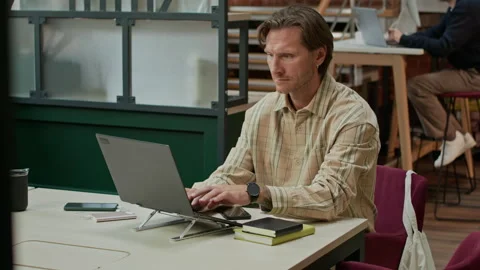 Middle-Aged Software Developer Working on Laptop in Modern Coworking Space Stock Footage 319998370