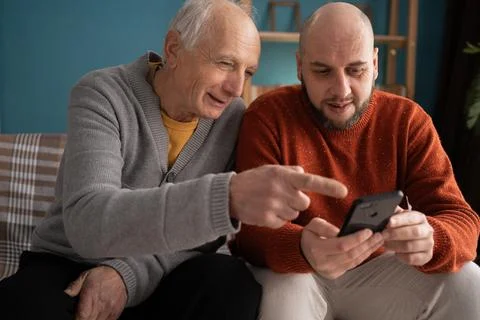 Middle-aged son helping and learning his elderly father shopping online and.. Stock Photos