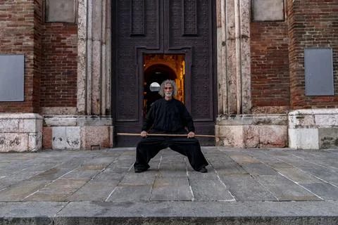Middle-aged tai chi master showing stick exercises outdoors amidst the arch.. Stock-Fotos