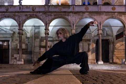 Middle aged tai chi master showing stick exercises outdoors amidst the arch.. Stock Photos