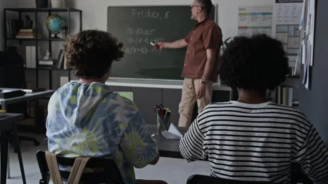 Middle Aged Teacher Explaining Math on Blackboard to Teenage Students Video stock 339662826