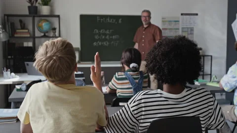 Middle Aged Teacher Explaining Math to Multiethnic Children in Classroom Stock Footage 339684909