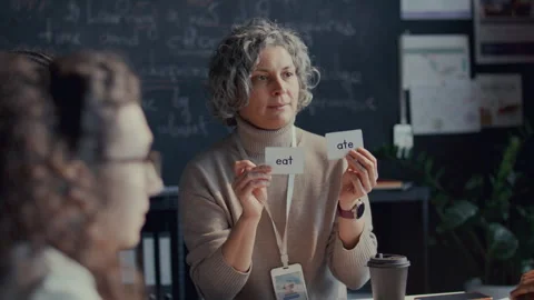 Middle-Aged Teacher Explaining Verb Tenses with Flashcards in English Class Stock Footage 295838567