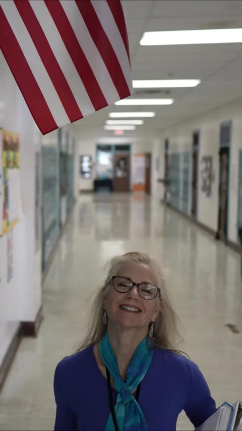 Middle-aged Teacher Walking in a School Hallway With Lockers and American Flag Stock Footage 307040221
