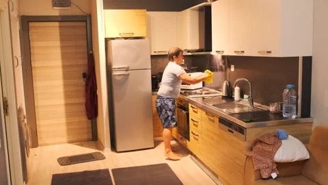Middle aged white man wiping backsplash surface medium view in kitchen, cleaning Stock Footage 333578289